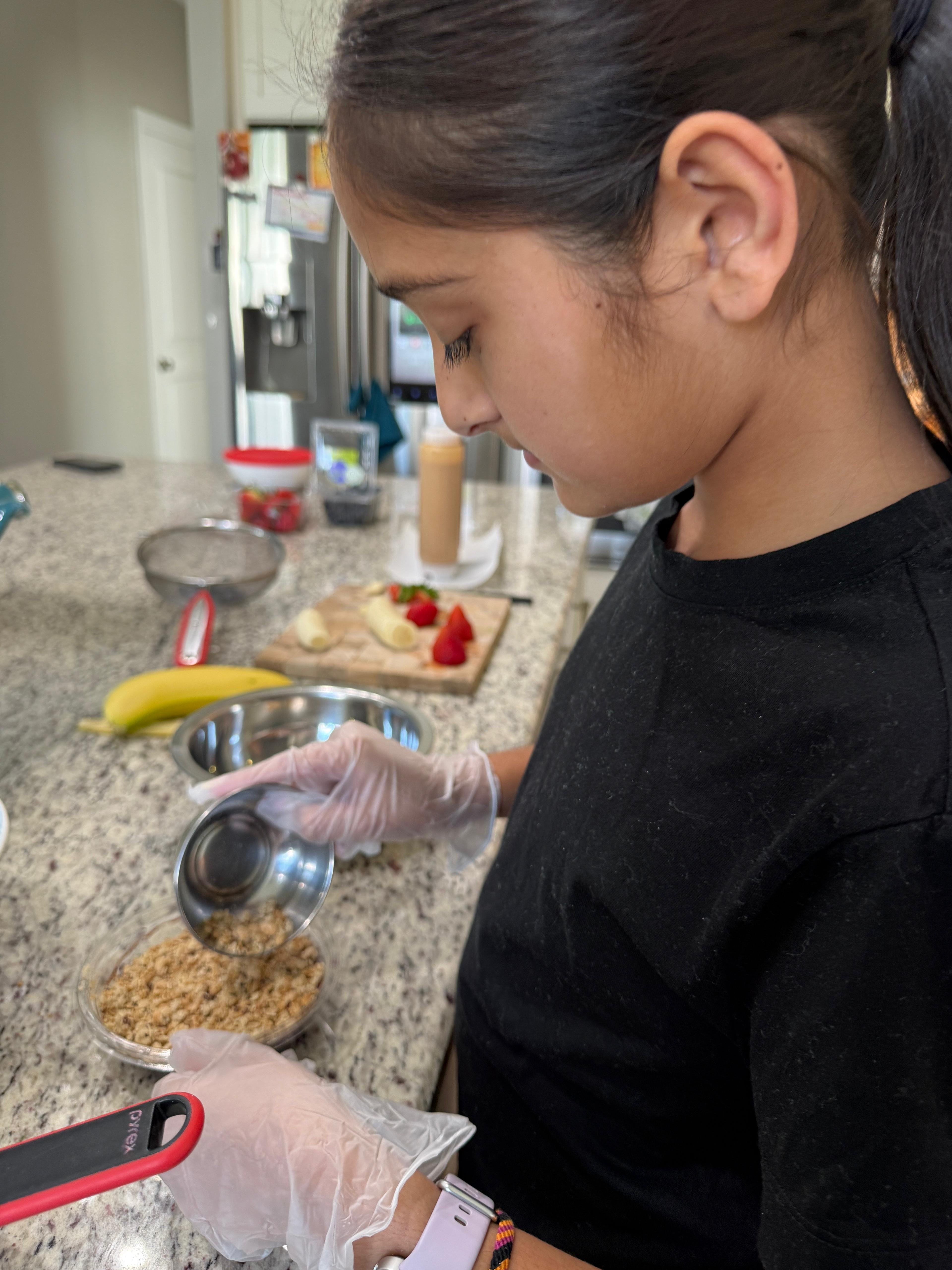 Arianna carefully measuring granola for a bowl